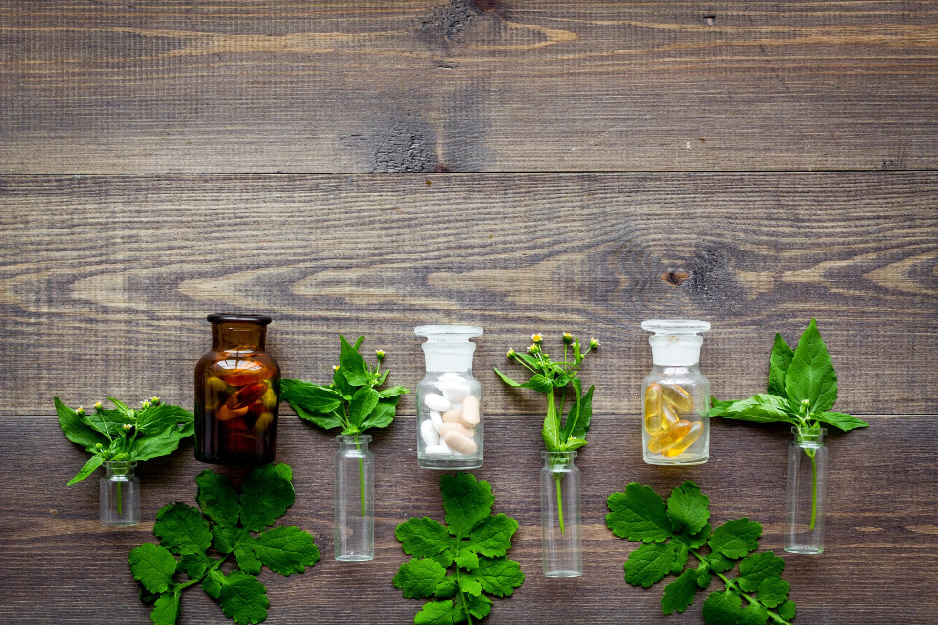 Herbal medicine pattern. Leaves, bottles and pills on wooden background top view copyspace Herbal medicine pattern. Leaves, bottles and pills on wooden background top view copyspace
